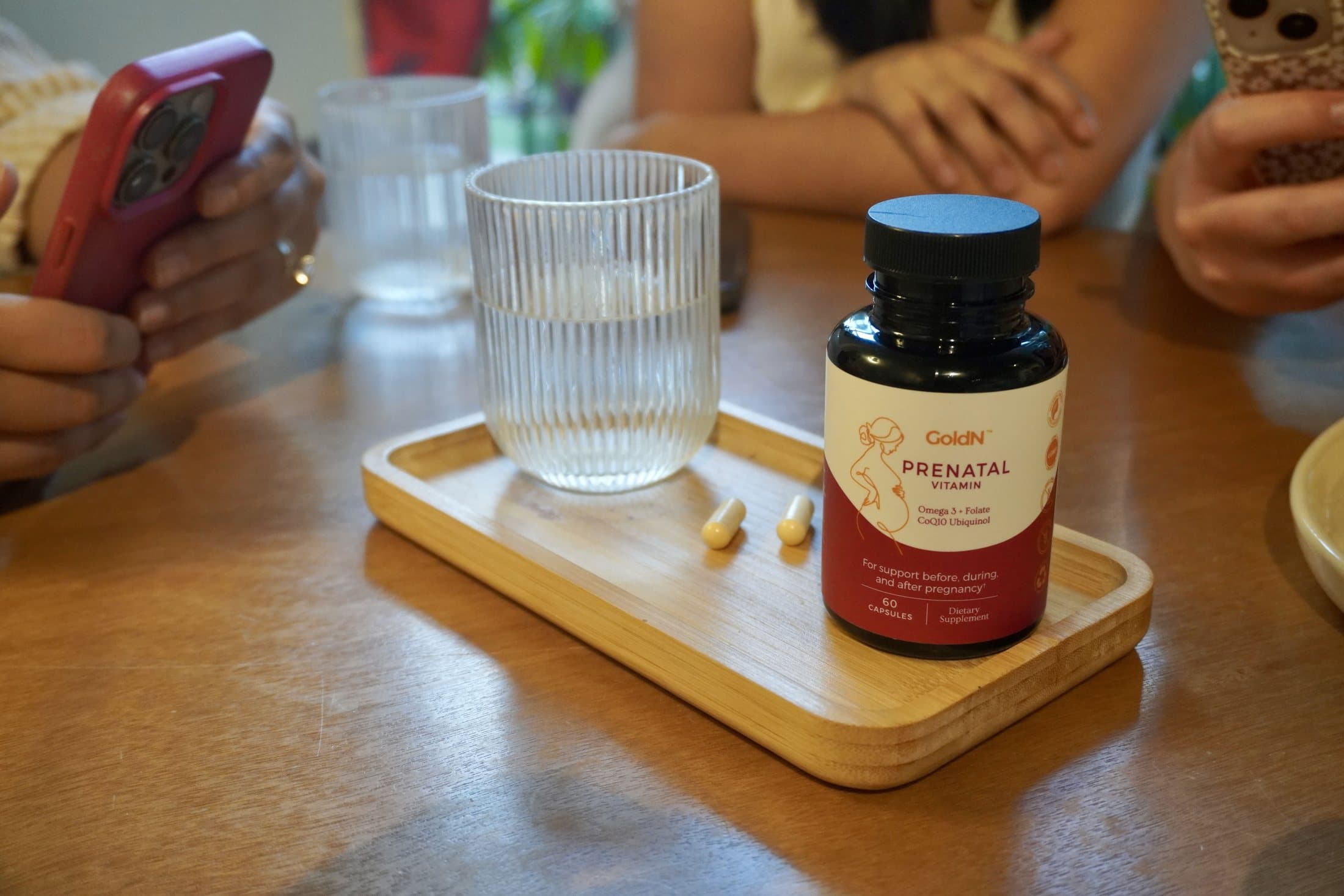 GoldN Prenatal bottle on a wooden tray at a table
